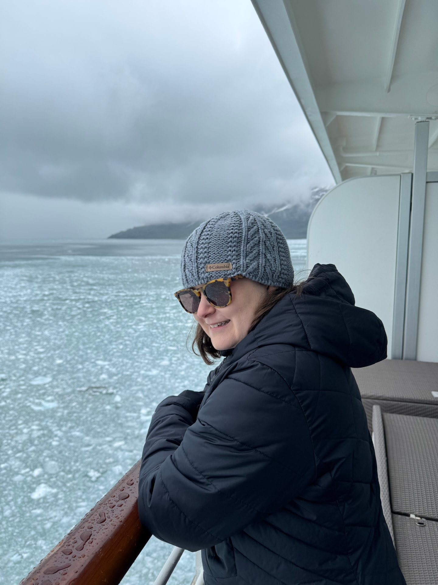 Guest on a private balcony watching ice drift past in an Alaskan fjord