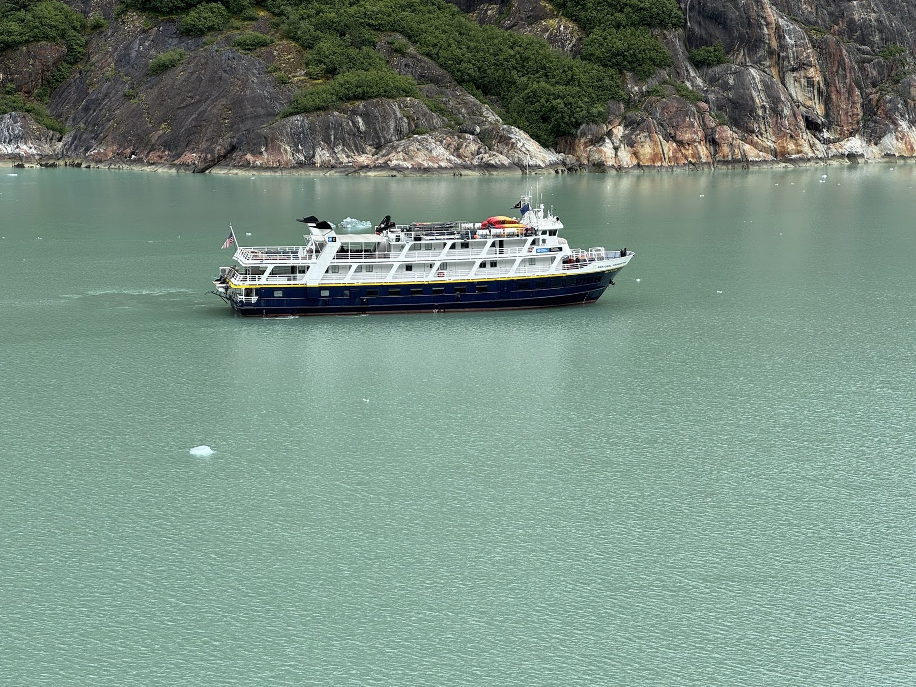Small expedition ship cruising a quiet Alaskan fjord