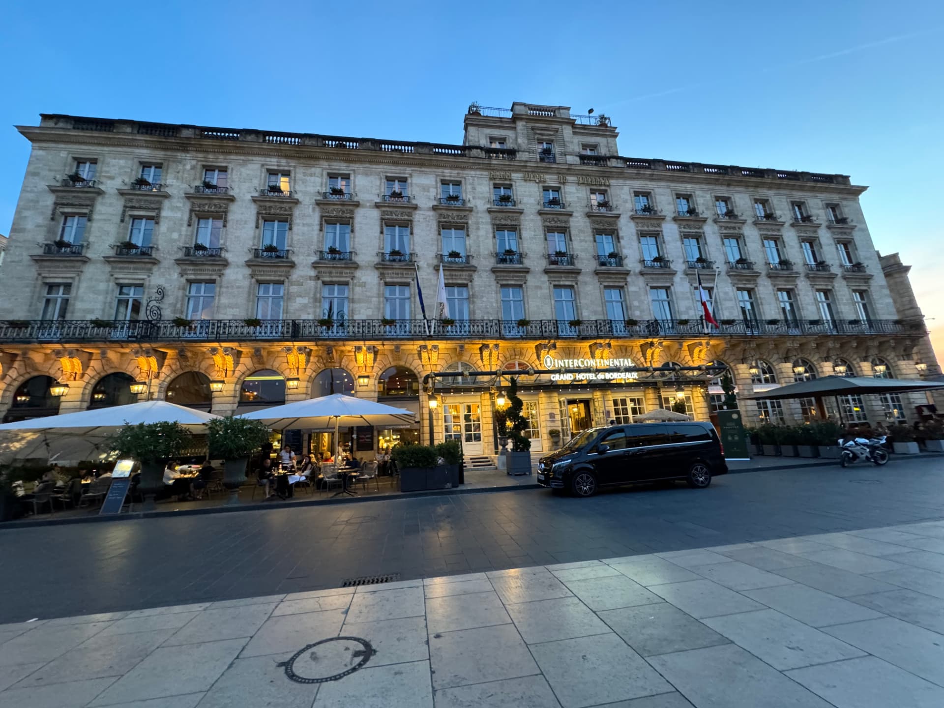 The grand hotel facade on Place de la Comédie lit up at dusk
