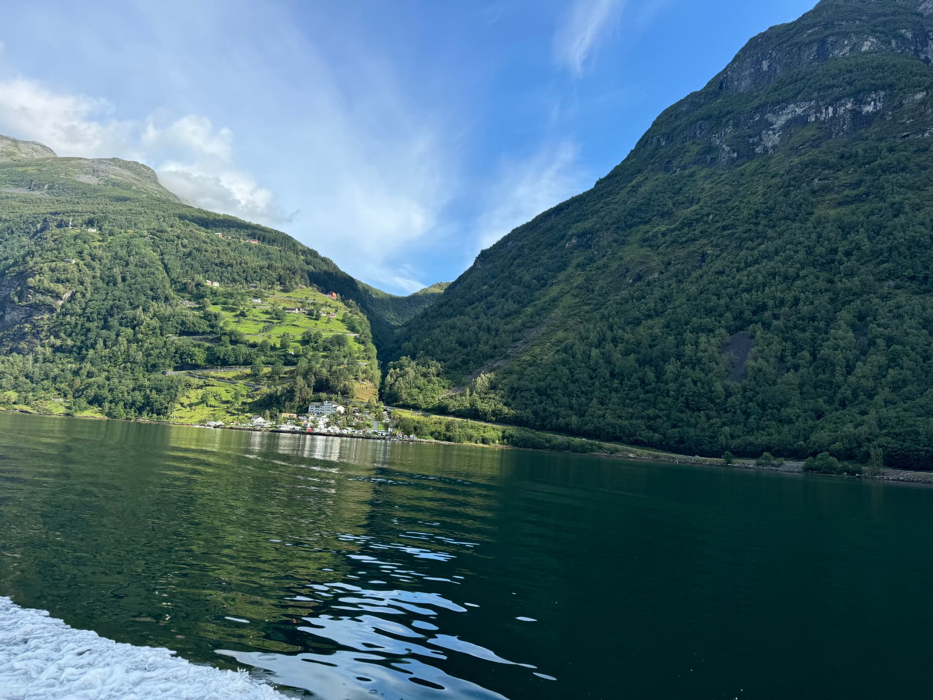 Sunny afternoon on Geirangerfjord with a village along the shore