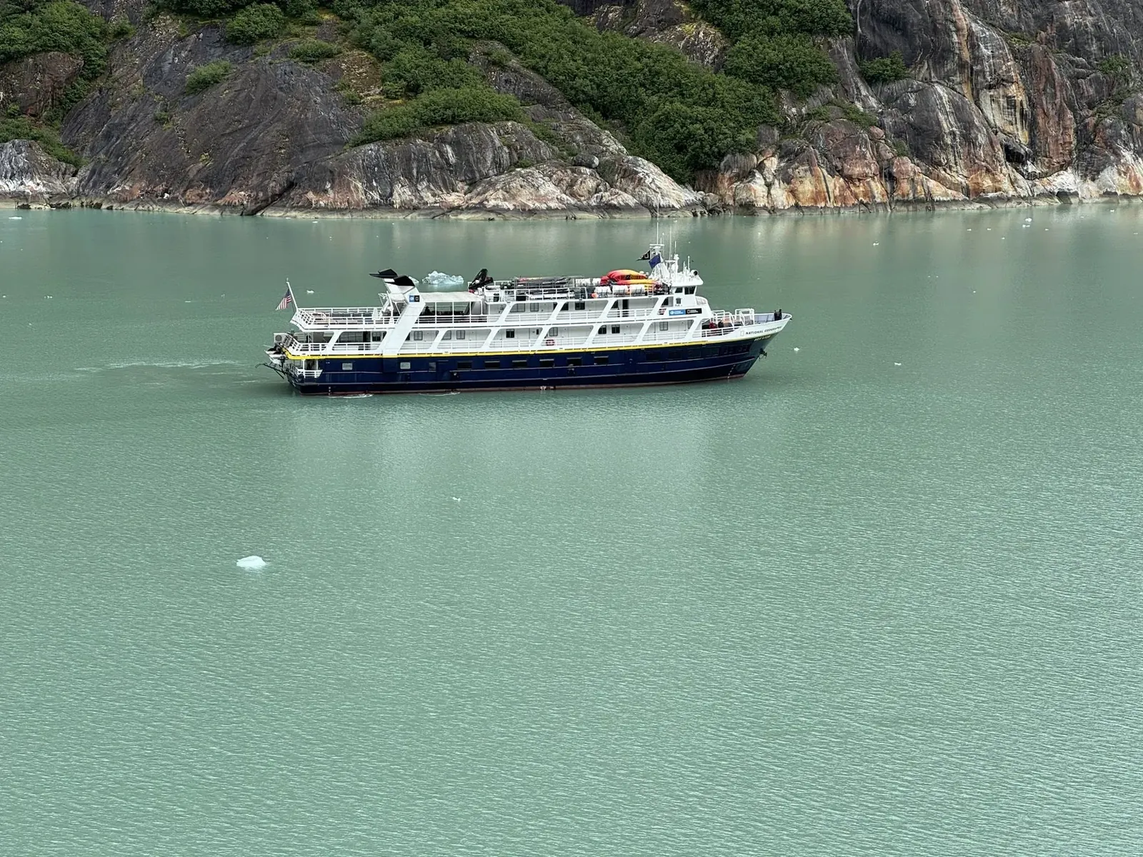 Small expedition ship cruising a quiet Alaskan fjord