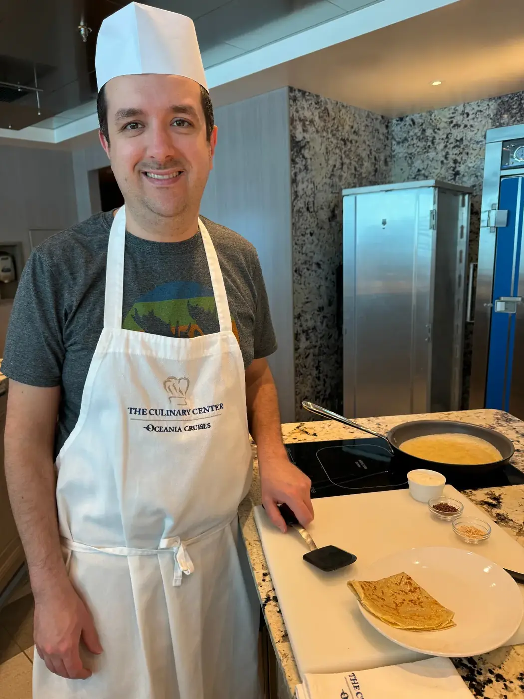 Ben in chef's hat and apron at The Culinary Center on an Oceania ship