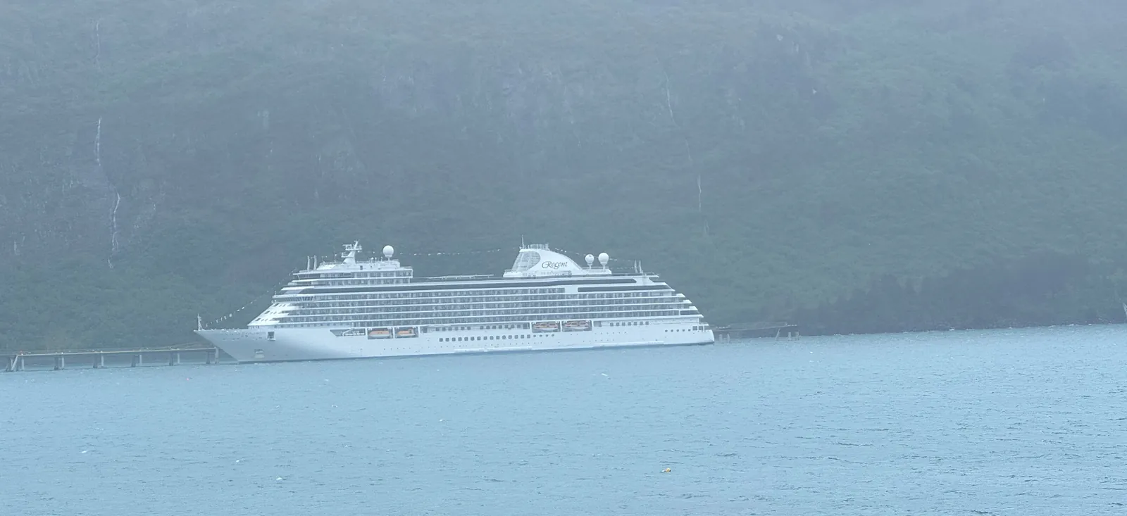 Regent Seven Seas ship sailing through a misty Norwegian fjord